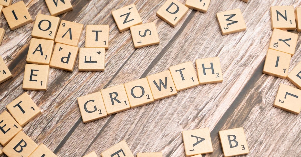 Scrabble tiles spelling 'growth' on a wooden surface symbolize progress and expansion.